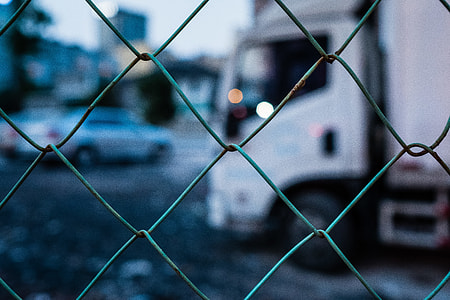 white delivery truck behind gray cyclone fence in tilt shift photography