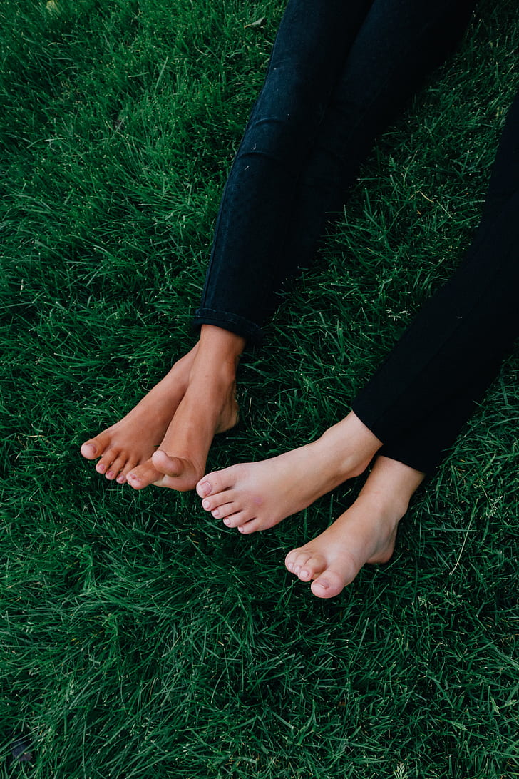 two person lying on green lawn grass wearing black denim jeans