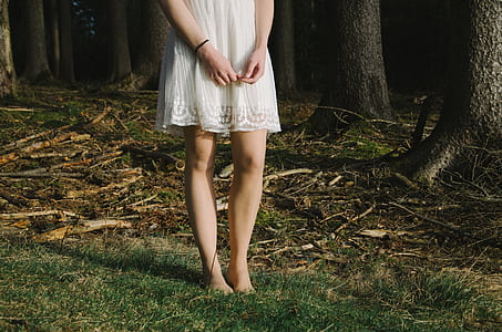 woman wearing white lace midi dress standing on green grass