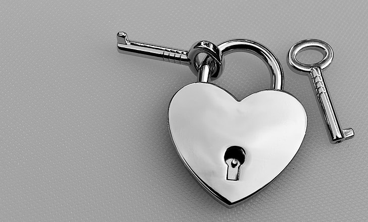 silver-colored heart padlock with key
