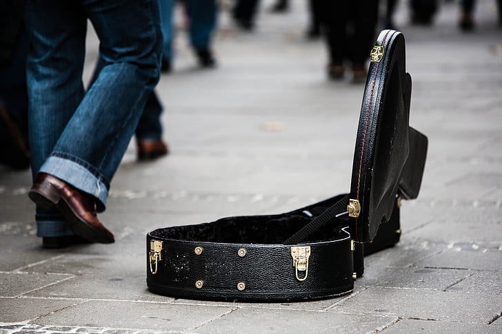 man wearing blue jeans beside the opened black leather guitar case