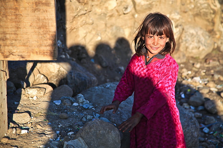 girl wearing pink dress near rocks