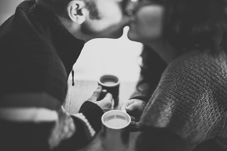 man and woman enjoying coffee while man pecks on woman
