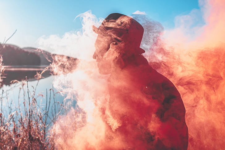 man in hat covered with orange smoke