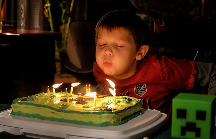 boy wearing red shirt blowing cake candles