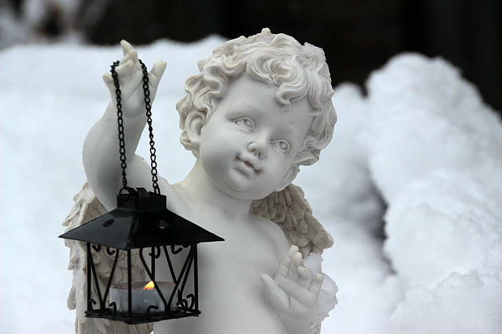 black candle lantern on cherub hand statue