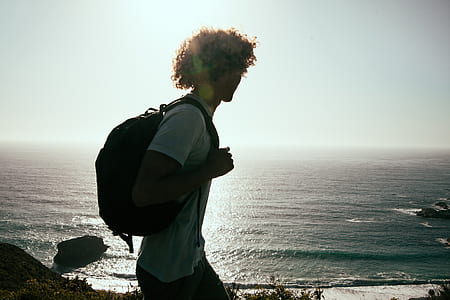 man carrying backpack with sea below