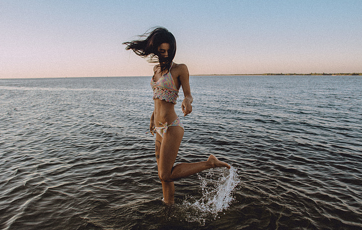 standing woman wearing beige lace trim bikini over body of water