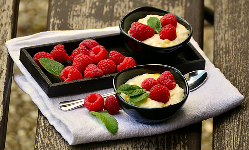 raspberries on black ceramic bowls