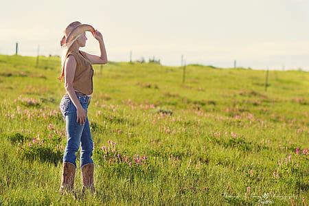 Woman Wearing Brown Cowboy Boots and Vest With Hat Under Blue Sky during Daytime