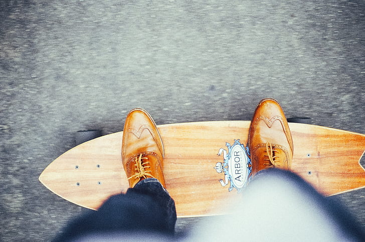 person riding brown Arbor pintail skateboard