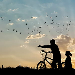 photo of boy and child holding bicycle during daytime