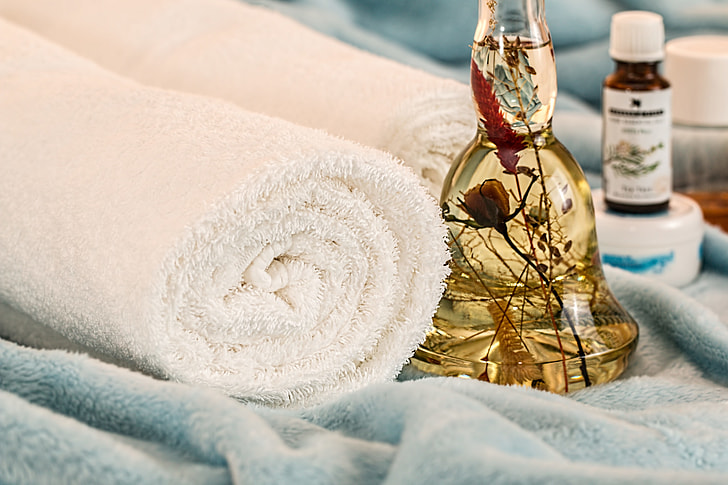 two white bath towels and clear glass bottle