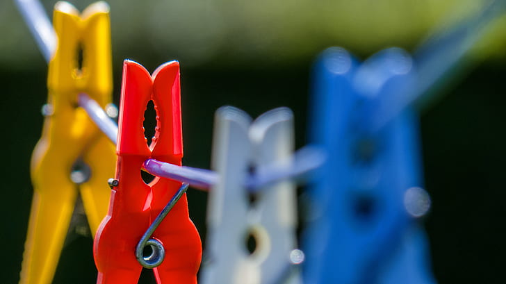 macrophotograph of red, blue, white, and yellow clothespin hanging on wire