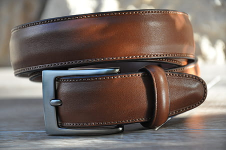 close up photography of rolled brown leather belt