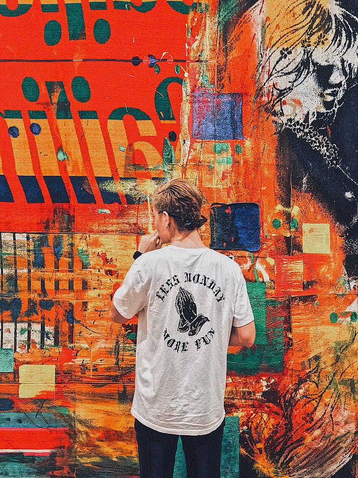 photo of man wearing shirt doing artwork on wall