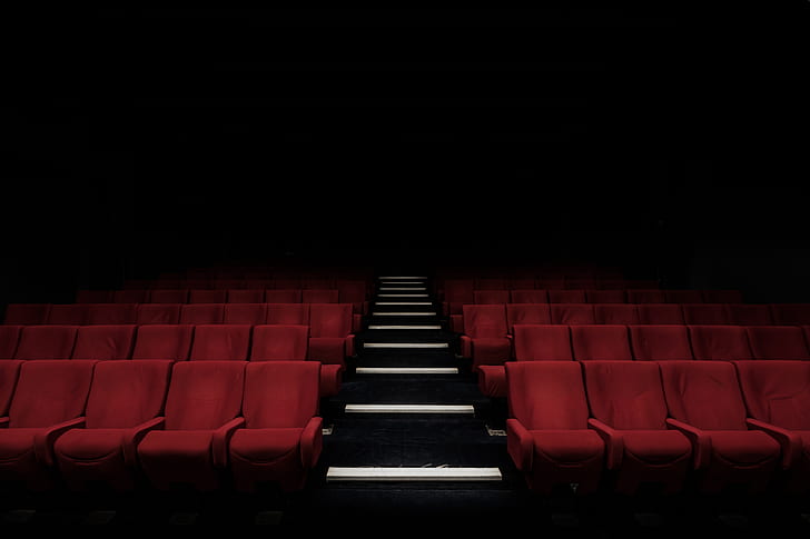 low angle photography of red chairs on theater