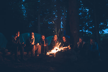 seven men sitting in front of bonfire during nighttime
