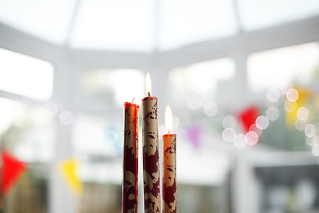 selective focus photography of three white-and-red lighted stick candles