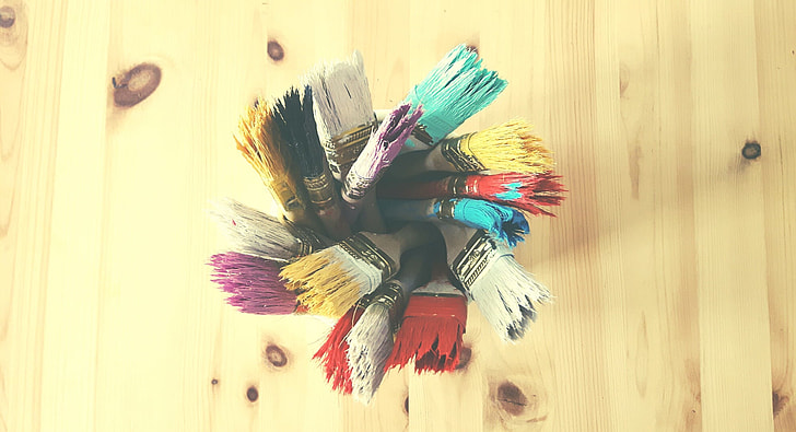 assorted-color paint brushes on beige table