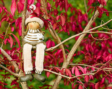 girl plush toy sitting on red leaf plant
