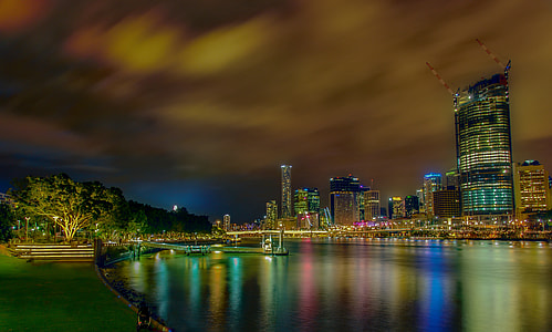 panoramic view of city buildings beside body of water nighttime