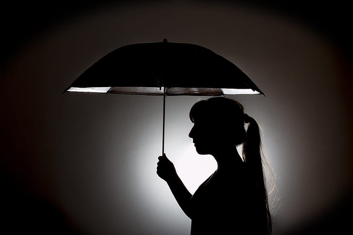 silhouette of woman holding umbrella