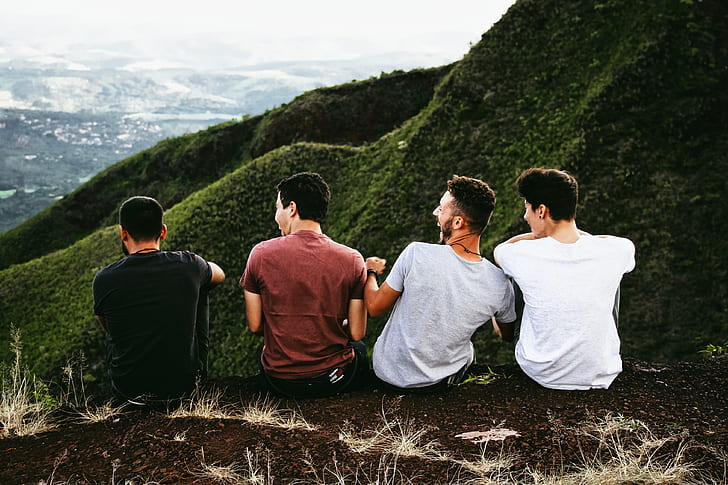four men sitting on brown ground photo during daytime
