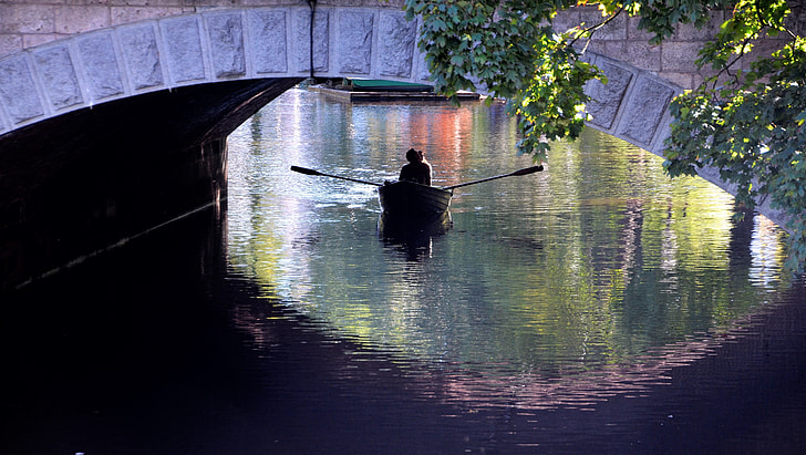 person riding paddle boat under bridge