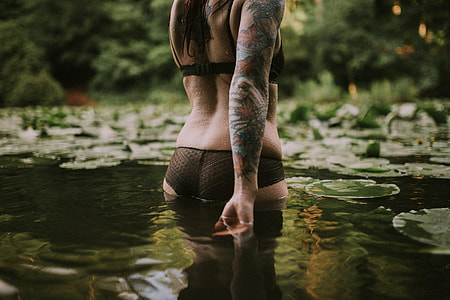 shallow focus photography of woman in black lingerie standing in body of water during daytime