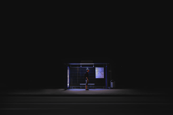 man in black shirt standing on waiting shed