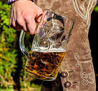 person holding clear glass beer mug
