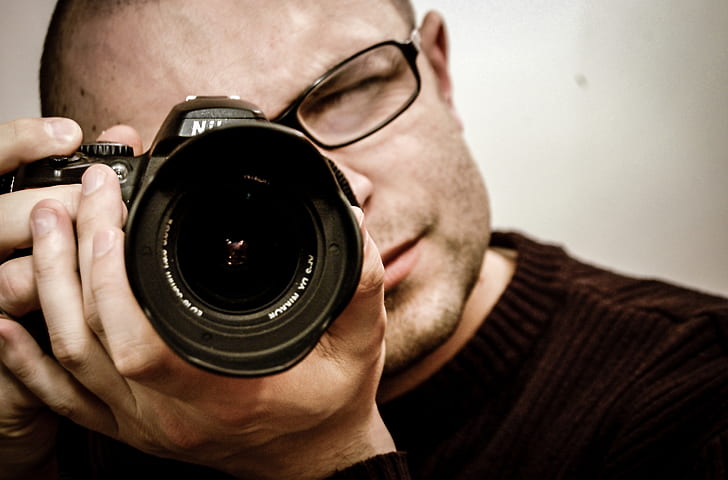man in black framed eyeglasses using black Nikon DSLR camera