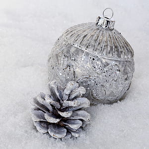 silver glitter bauble and white painted pine cone on fur textile