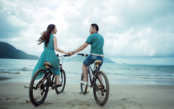 man and woman riding bicycle on seashore
