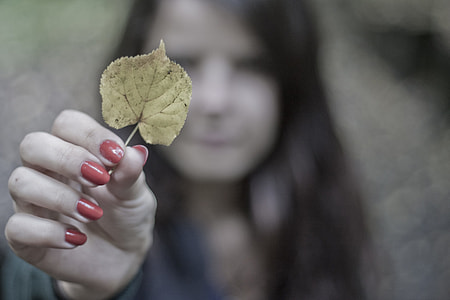selective focus of woman holding yellow leaf