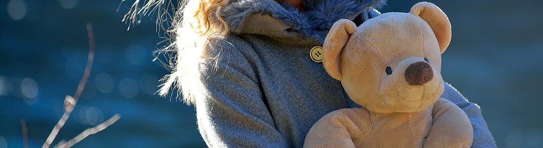 person holding beige bear plush toy