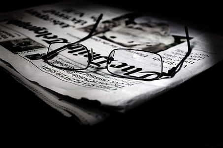 closeup photo of eyeglasses on newspaper