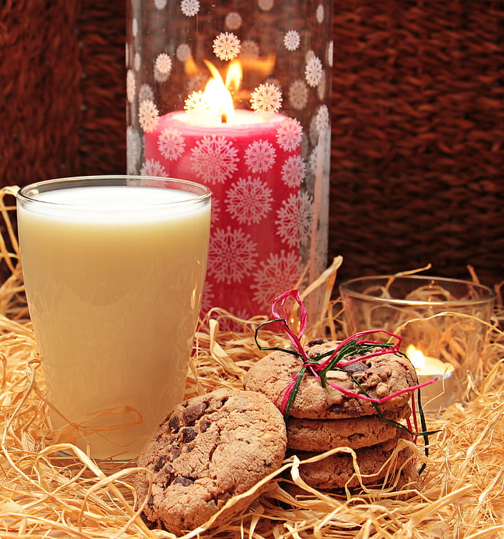 chocolate chip cookies beside glass of milk and red pillar candle