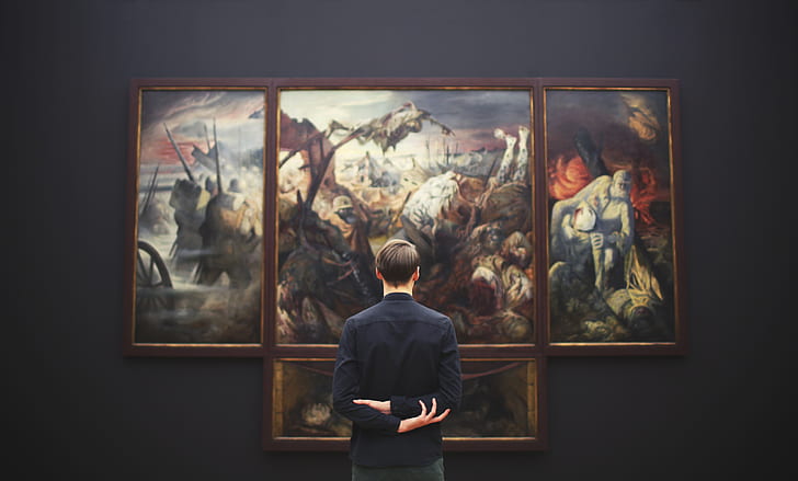 man in black dress shirt looking at paintings