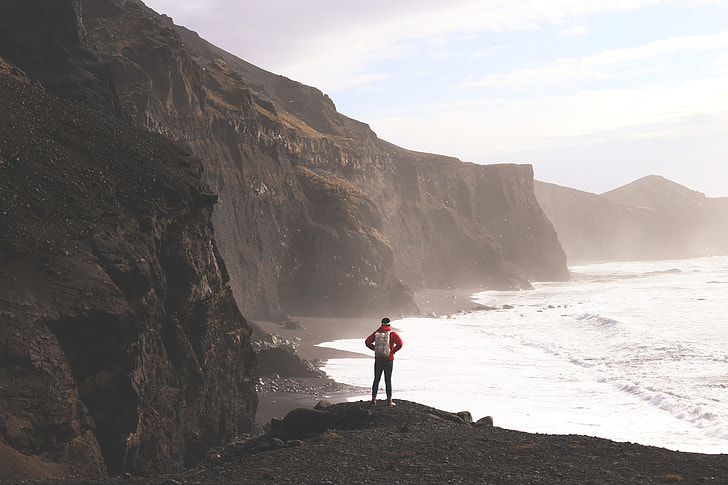 A hiker man stands on the dramatic coast of Iceland