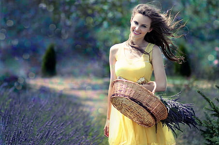 woman in yellow sleeveless dress carrying brown basket