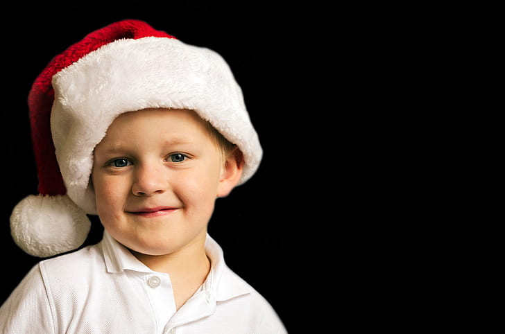 boy wearing white polo shirt and Santa hat on black background