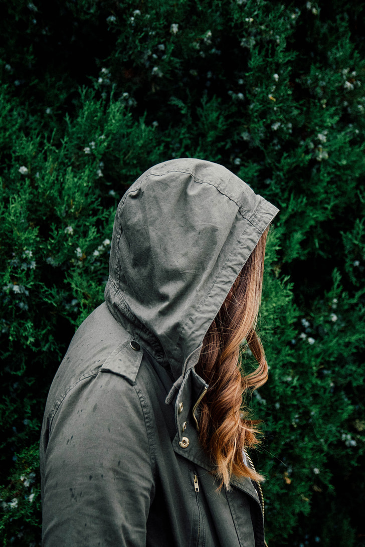 blonde-hair woman in gray hooded jacket near plant