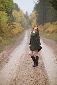 photo of a woman wearing green scoop-neck dress standing on the road