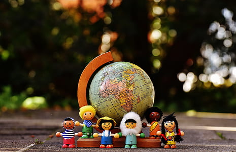 group of people character plastic toys standing on brown and blue desk globe photo