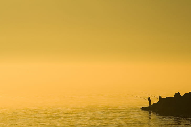 silhouette of person holding fishing rod