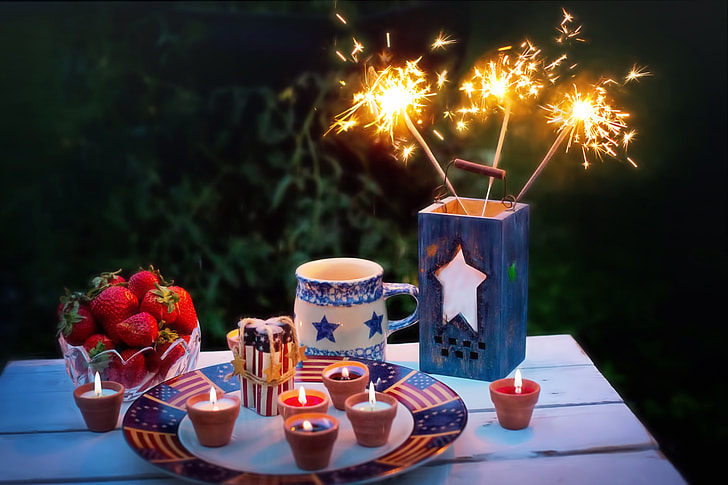 sparkler on container beside tealights on table
