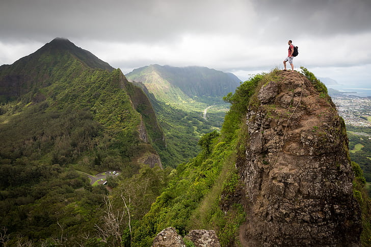 photography of man wearing backpack standing on cliff