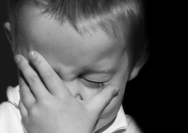 grayscale photography of boy holding his face